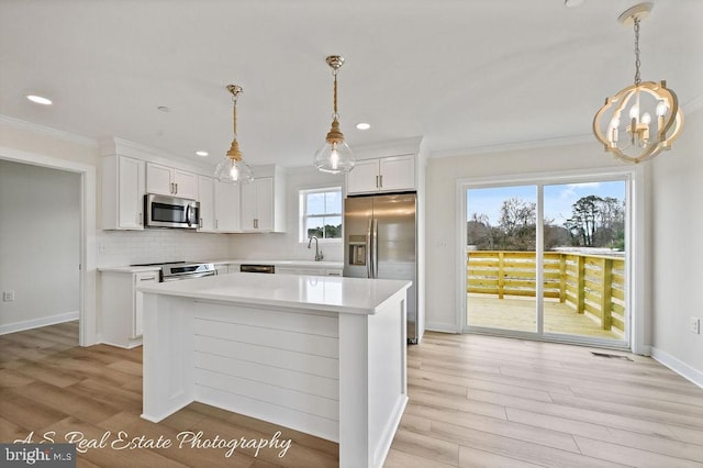 kitchen with white cabinetry, appliances with stainless steel finishes, and decorative light fixtures