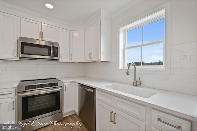 kitchen with white cabinetry, sink, light stone counters, and appliances with stainless steel finishes