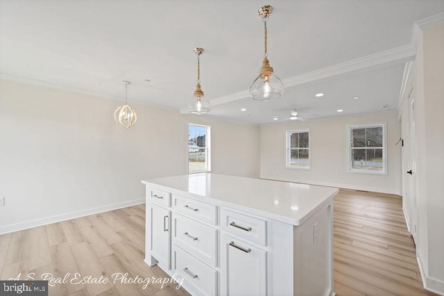 kitchen with crown molding, a center island, light hardwood / wood-style flooring, hanging light fixtures, and white cabinets