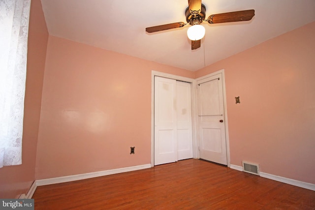 unfurnished bedroom with hardwood / wood-style flooring, ceiling fan, and a closet