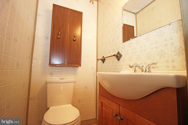 bathroom with vanity, toilet, and tile walls