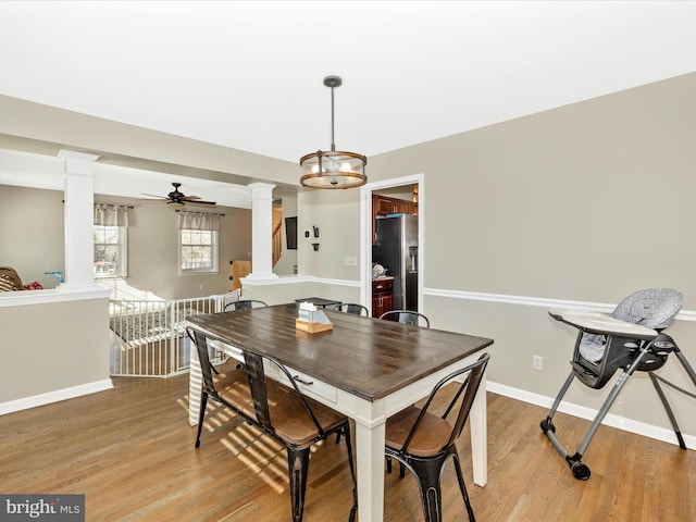 dining area featuring decorative columns, ceiling fan with notable chandelier, and light wood-type flooring