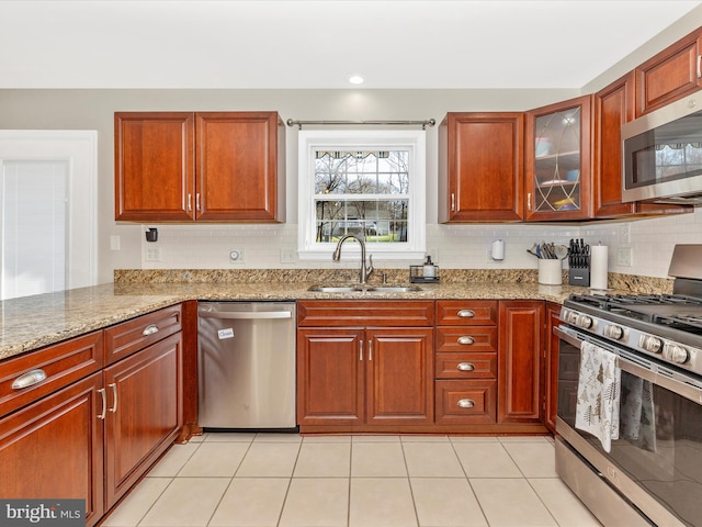 kitchen featuring light stone countertops, sink, light tile patterned floors, and stainless steel appliances