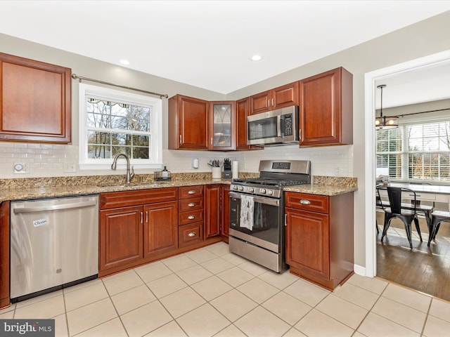 kitchen featuring plenty of natural light, sink, light stone countertops, and stainless steel appliances