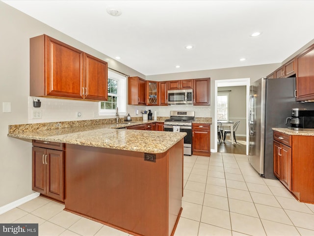 kitchen with kitchen peninsula, light stone counters, stainless steel appliances, sink, and light tile patterned flooring