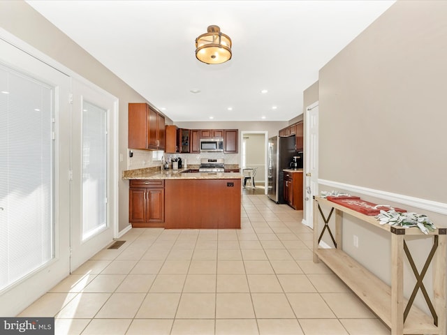 kitchen with kitchen peninsula, light tile patterned floors, stainless steel appliances, and light stone countertops