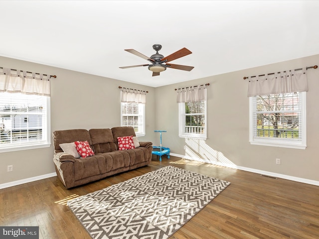 living room featuring dark hardwood / wood-style flooring, ceiling fan, and a healthy amount of sunlight