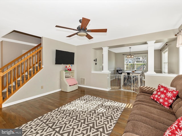 living room with ceiling fan with notable chandelier and dark hardwood / wood-style flooring