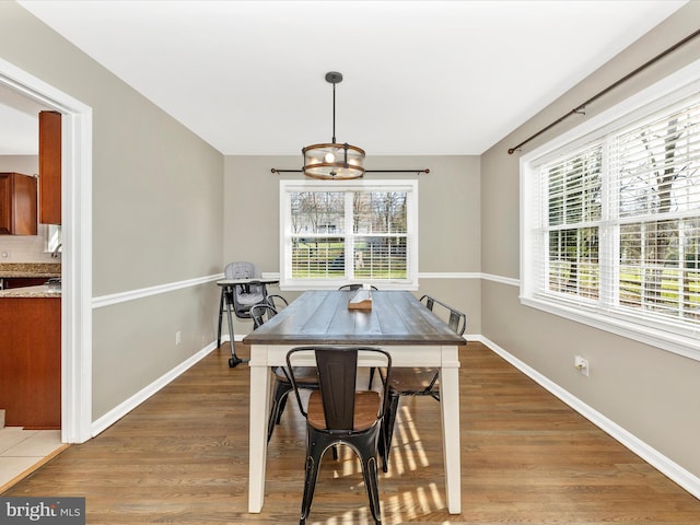 dining space with hardwood / wood-style floors and a notable chandelier