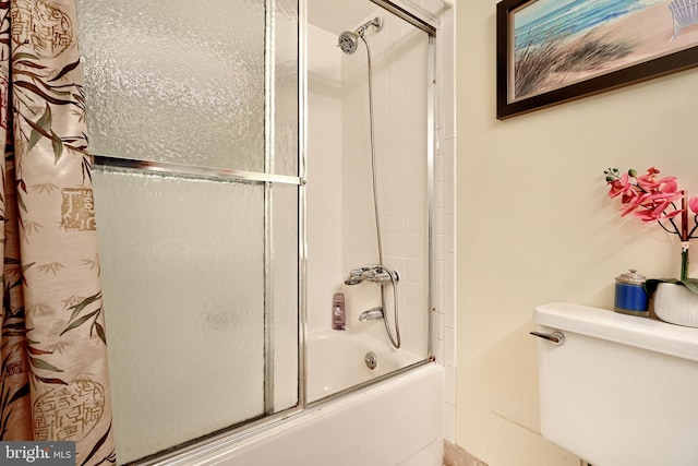 bathroom with toilet and shower / bath combination with glass door