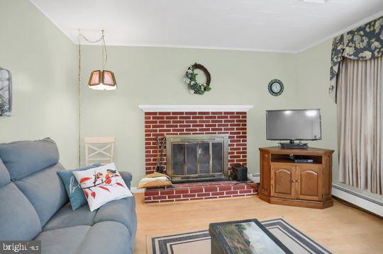 living room with a fireplace, hardwood / wood-style floors, and a baseboard heating unit