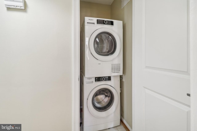 washroom with stacked washing maching and dryer and light tile patterned floors