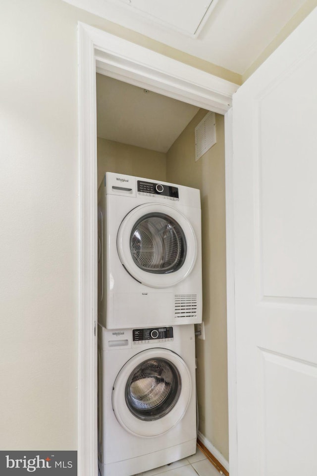 laundry room with stacked washer and dryer and light tile patterned floors