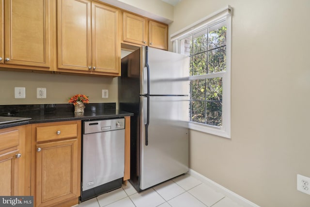 kitchen featuring light tile patterned flooring, dark stone counters, and appliances with stainless steel finishes