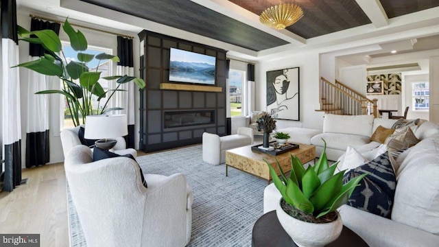 living room with beamed ceiling, light hardwood / wood-style floors, a fireplace, and coffered ceiling