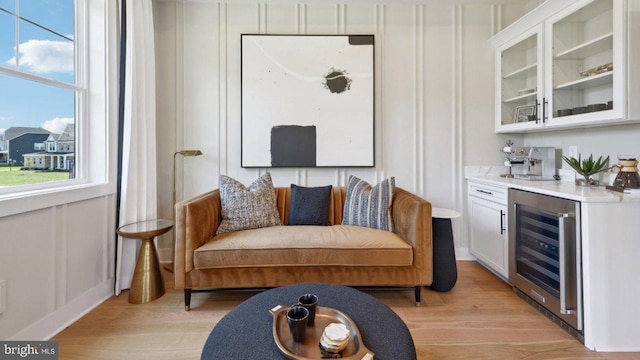 interior space with wine cooler, light hardwood / wood-style floors, and white cabinets