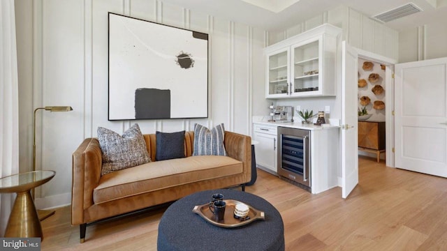 bar featuring white cabinets, beverage cooler, and light hardwood / wood-style flooring