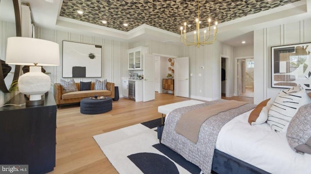 bedroom featuring a tray ceiling, ornamental molding, light hardwood / wood-style floors, and a chandelier