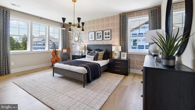 bedroom featuring brick wall, a notable chandelier, and light hardwood / wood-style floors