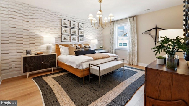 bedroom with light hardwood / wood-style flooring and a notable chandelier