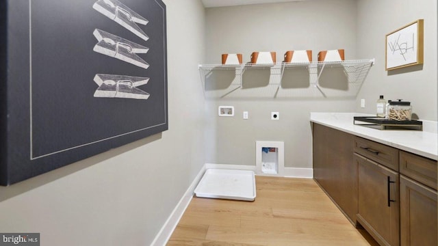 laundry area featuring hookup for a washing machine, electric dryer hookup, cabinets, and light hardwood / wood-style floors