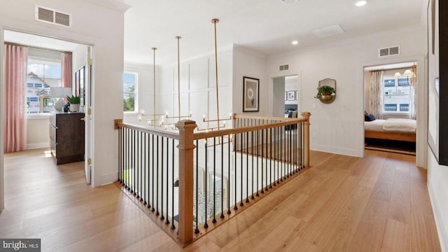 corridor with light hardwood / wood-style flooring and ornamental molding