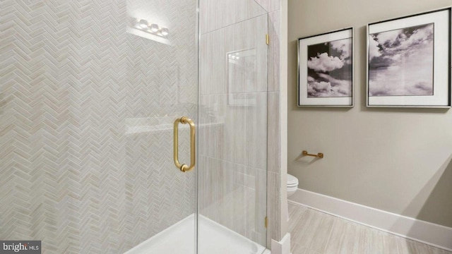 bathroom with a shower with shower door and toilet