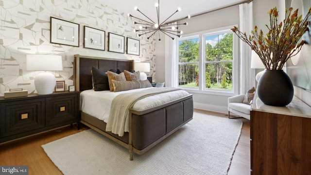 bedroom featuring multiple windows, wood-type flooring, and an inviting chandelier