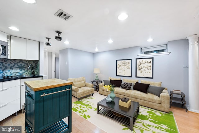 living room with light wood-type flooring and decorative columns