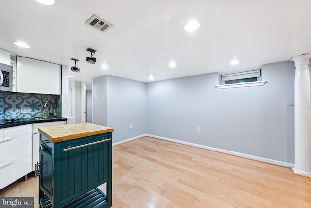 kitchen with a center island, wood counters, light hardwood / wood-style flooring, decorative backsplash, and white cabinets