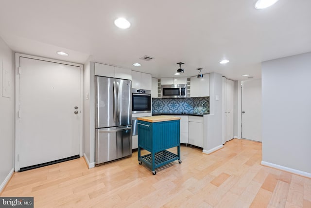 kitchen with wooden counters, light wood-type flooring, appliances with stainless steel finishes, a kitchen island, and white cabinetry