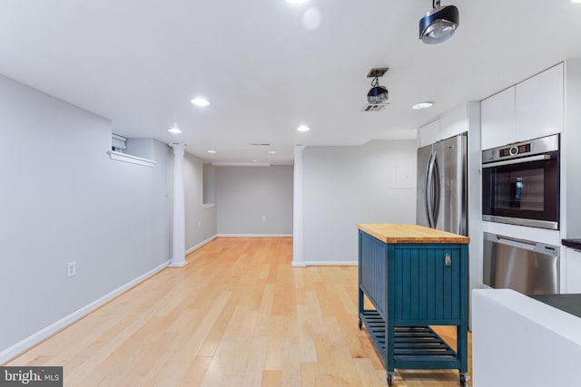 kitchen with wooden counters, light wood-type flooring, blue cabinetry, white cabinetry, and stainless steel appliances