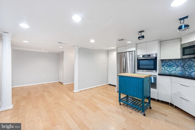 kitchen featuring wooden counters, decorative columns, stainless steel appliances, white cabinets, and light hardwood / wood-style floors