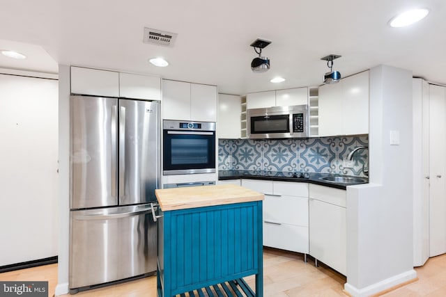 kitchen with a center island, sink, decorative light fixtures, white cabinets, and appliances with stainless steel finishes