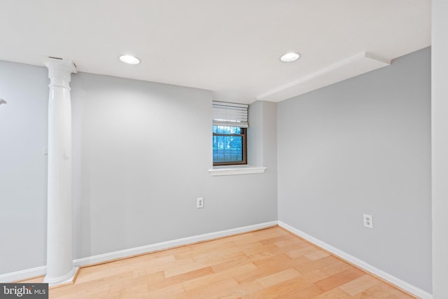 spare room featuring hardwood / wood-style floors and decorative columns