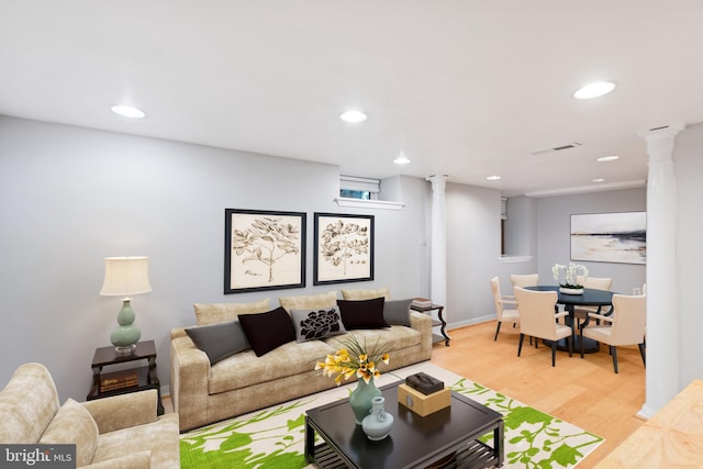 living room with decorative columns and light hardwood / wood-style flooring