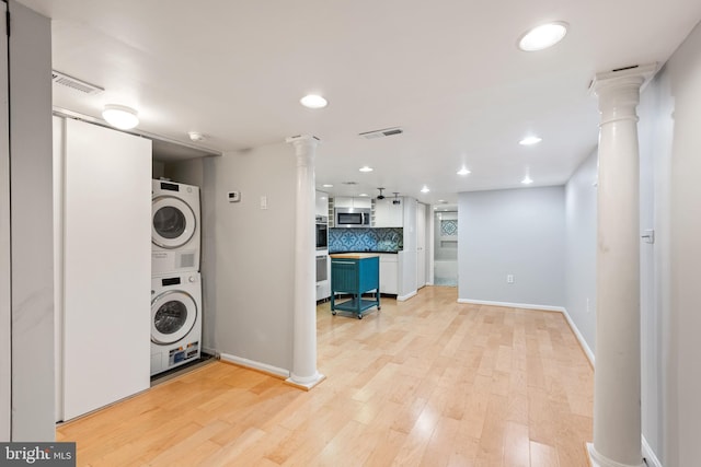 laundry room featuring stacked washer and dryer, ornate columns, and light hardwood / wood-style floors