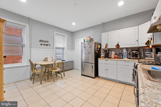 kitchen with appliances with stainless steel finishes, white cabinetry, and light stone counters