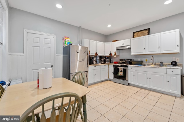 kitchen featuring white cabinets, appliances with stainless steel finishes, light tile patterned floors, and sink