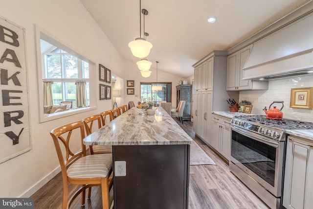 kitchen featuring a kitchen breakfast bar, gray cabinetry, gas stove, vaulted ceiling, and a kitchen island