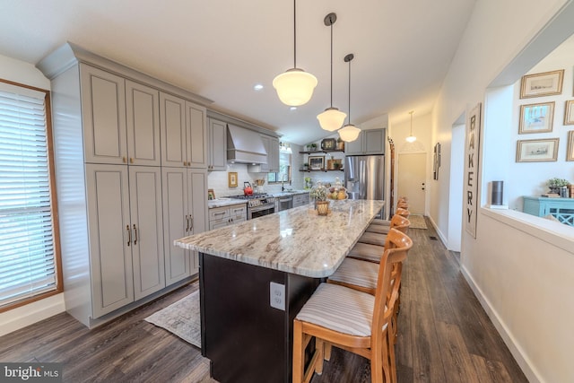 kitchen featuring custom exhaust hood, a kitchen breakfast bar, hanging light fixtures, a kitchen island, and stainless steel appliances