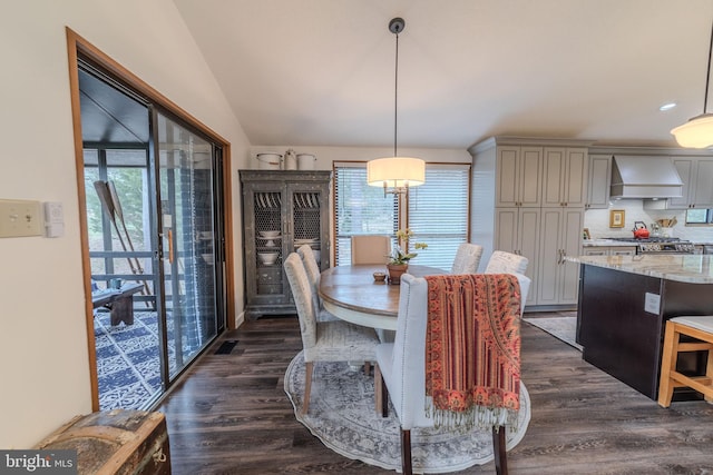 dining room with dark wood-type flooring and vaulted ceiling