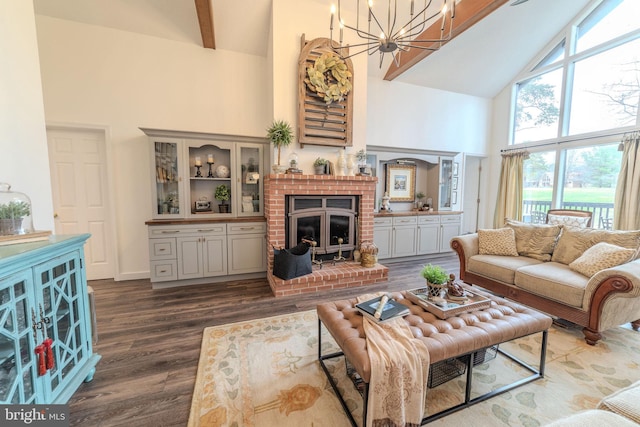 living room featuring dark wood-type flooring, high vaulted ceiling, a fireplace, beam ceiling, and a chandelier