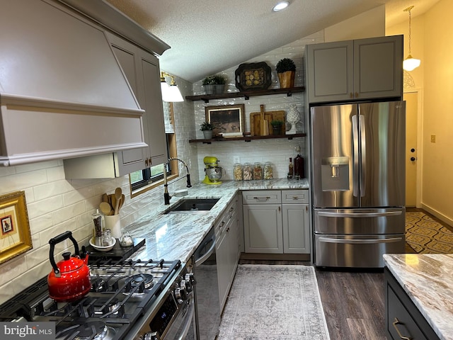 kitchen with light stone countertops, lofted ceiling, and stainless steel appliances