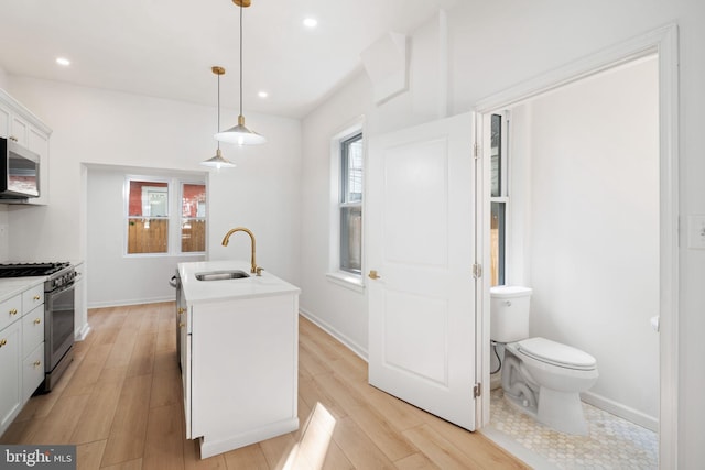 kitchen with pendant lighting, sink, an island with sink, light hardwood / wood-style floors, and stainless steel appliances