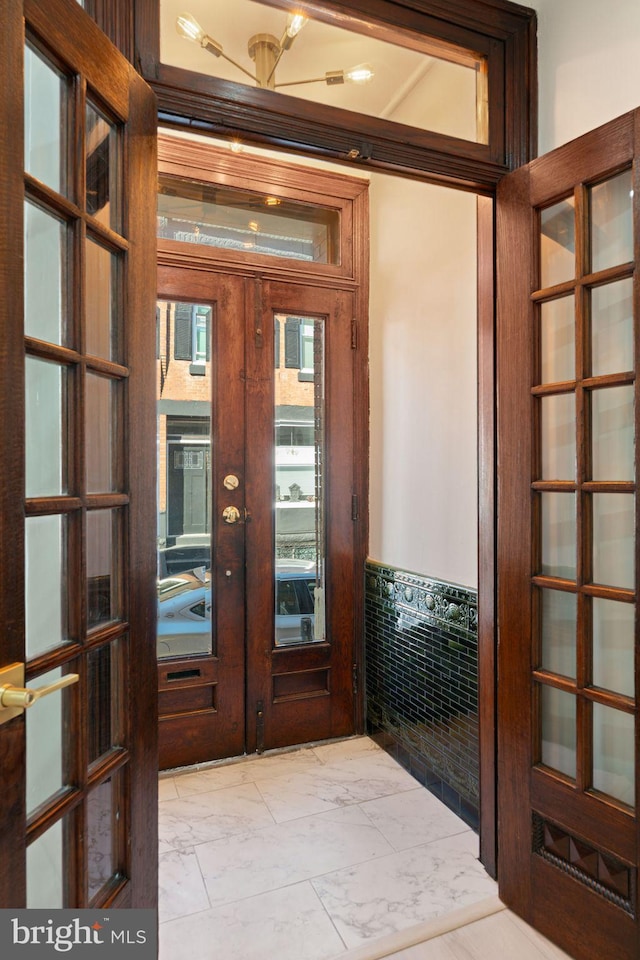 doorway with ornamental molding and french doors