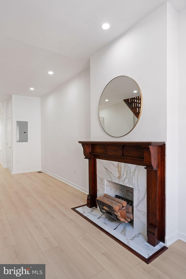 unfurnished living room with a high end fireplace, light wood-type flooring, and electric panel