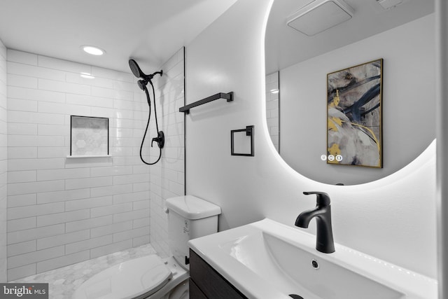 bathroom featuring tiled shower, vanity, and toilet