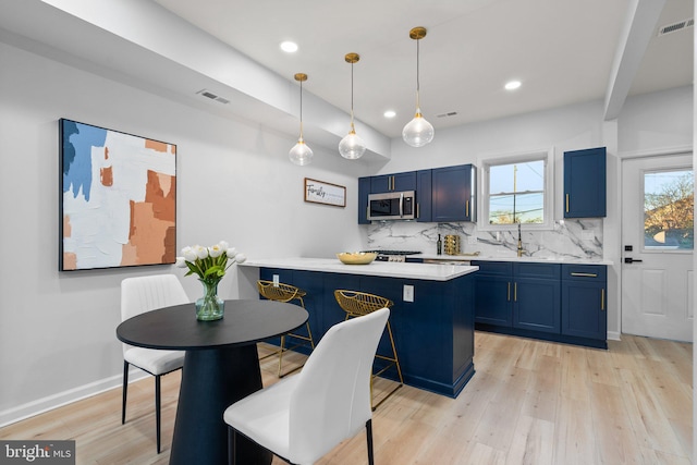 kitchen with blue cabinets, decorative light fixtures, and appliances with stainless steel finishes