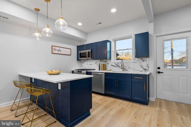 kitchen featuring appliances with stainless steel finishes, blue cabinets, and a healthy amount of sunlight